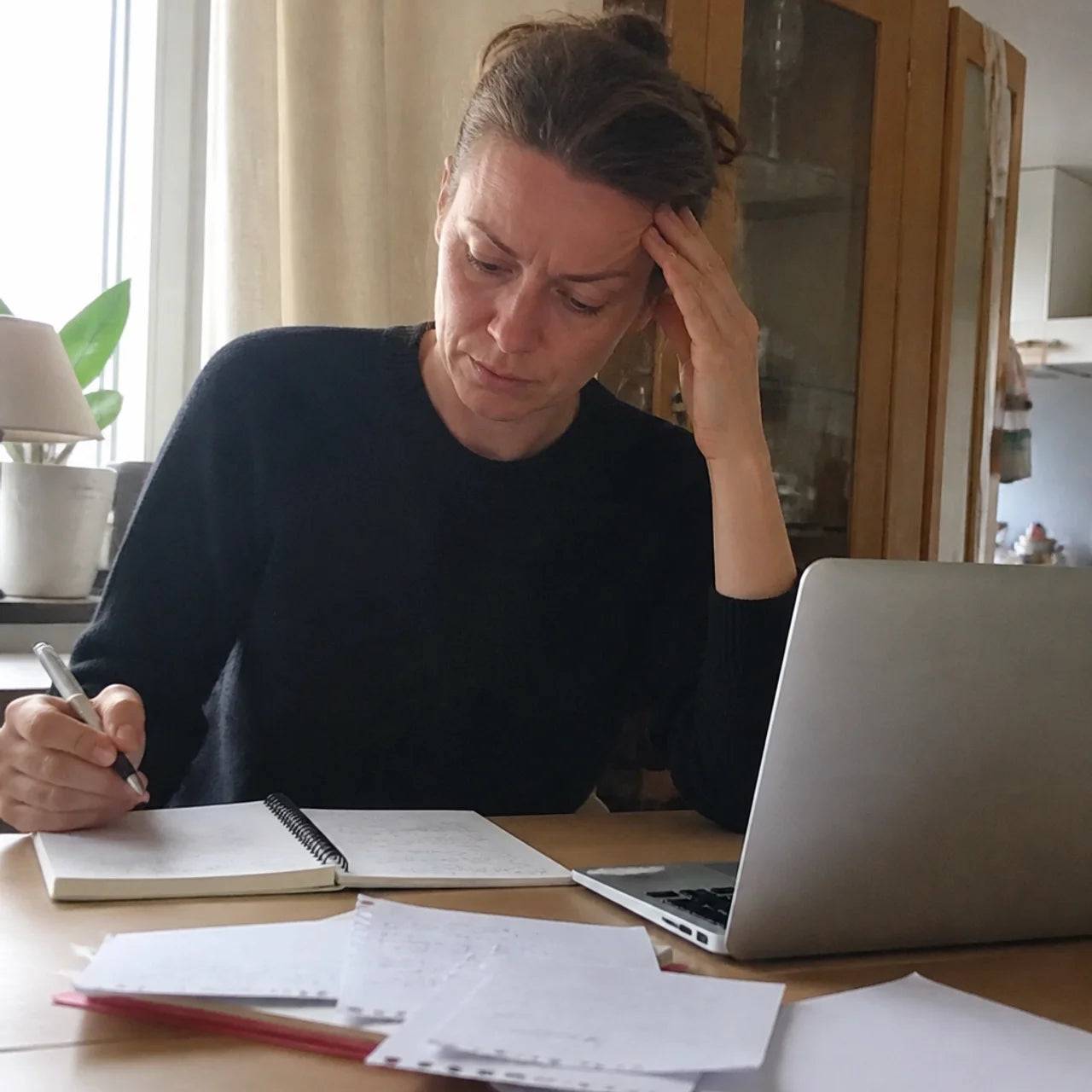 Frau versucht sich bei der Arbeit am Küchentisch zu konzentrieren